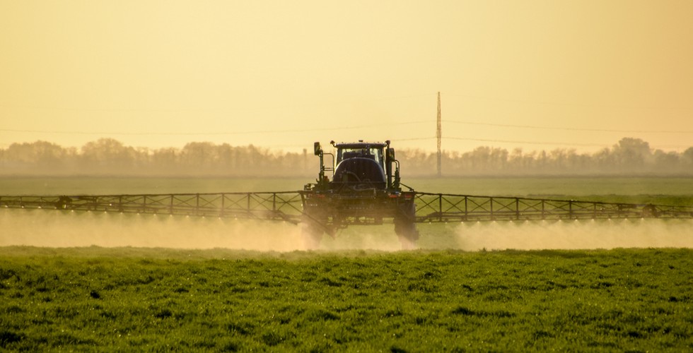 A tractor sprays glyphosate over a field.